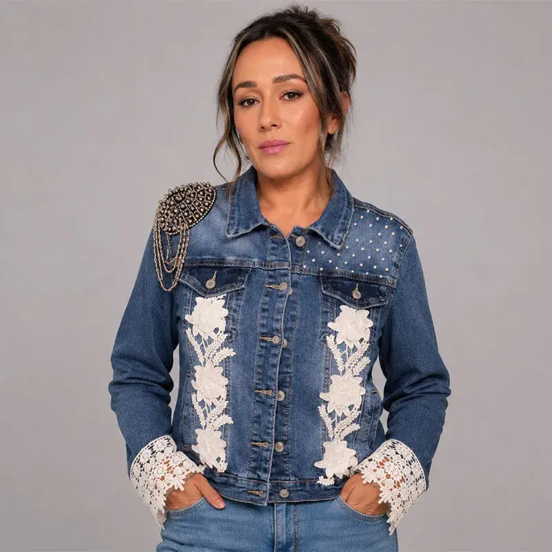 Vista delantera de chaqueta denim decorada con encaje floral blanco, estoperoles y hombrera con cadenas
