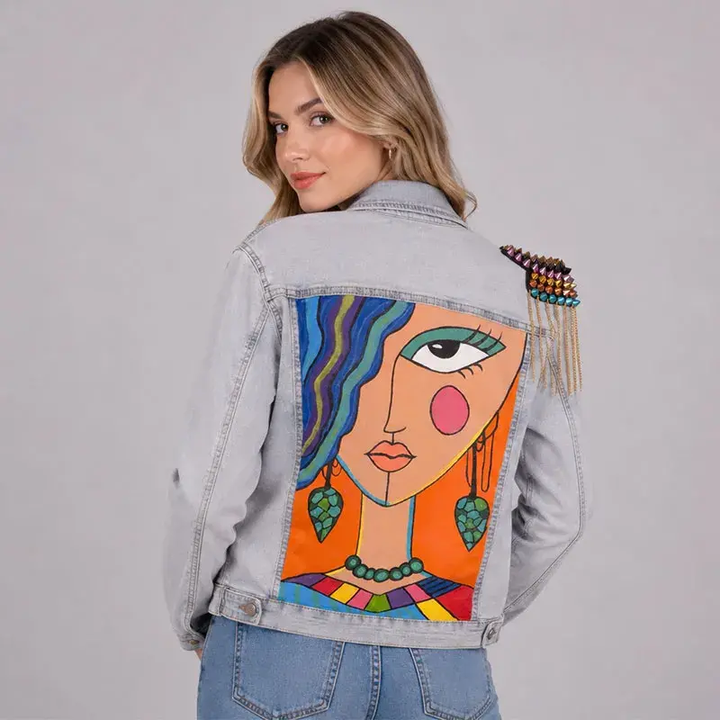 Vista trasera de chamarra denim con intervención artística pintada a mano y hombrera con cadenas - Trece31