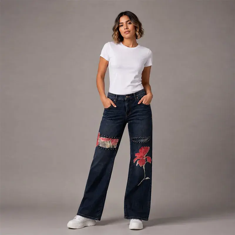 Pantalón de mezclilla corte vaquero intervenido con parches florales rojos y detalles de diseño único en las piernas